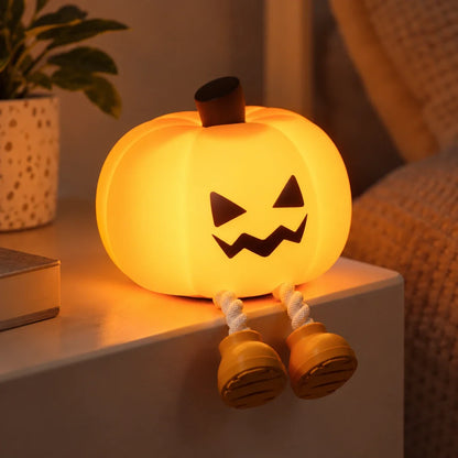 Silicone pumpkin lamp with the cheeky face, lit up next to some books